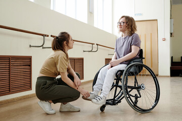 Fototapeta na wymiar Professional dance coach talking to cheerful young woman with disability in wheelchair during break time