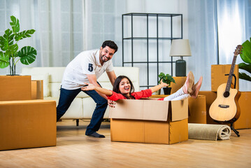 indian woman sitting inside cardboard box on moving day and husband pushing her
