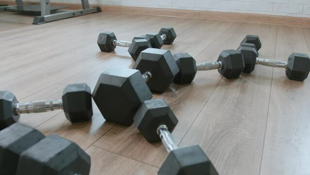 Row of dumbbells different sizes are laid out on floor of gym in form of a figure. Strength training equipment