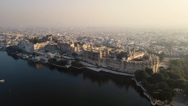 An aerial view of Lake Pichola with a City Palace view in Udaipur in the morning. The city, famously known as the "City of Lakes," is situated amidst the Aravalli Range. Udaipur, Rajasthan, India. 4k 