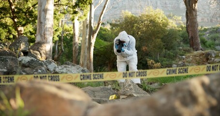 Forensic, photographer and evidence at crime scene for investigation in forest with police tape and...