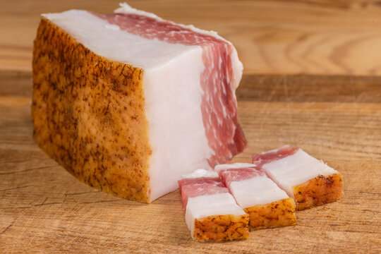 Slices and piece of salted pork fatback on cutting board