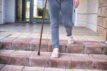 Senior woman on a rehabilitation after surgery with walking cane outdoors. - obrazy, fototapety, plakaty