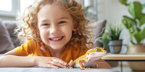 Cute young child holding her pet gecko in sunny living room. Kid and her best reptile friend at home.
