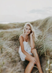 Serene Beachside Serenity: Blonde Woman Contemplating Life Amongst Whistling Dunes at Sunset - 775693716