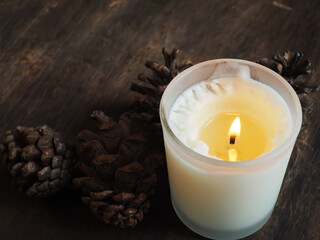 Scented candles on old wooden floor with dried pine cones for spa, relaxation at home 