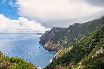 Fototapeta premium A picturesque coastal landscape in Madeira. Visible are houses surrounded by greenery, mountains, and the azure sea. The harmony of nature and human habitation.