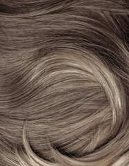 Brown hair close-up as a background. Women's long brown hair. Beautifully styled wavy shiny curls....