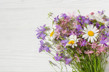 A bouquet of wildflowers lie on a white wooden surface
