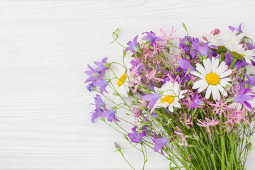 A bouquet of wildflowers lie on a white wooden surface