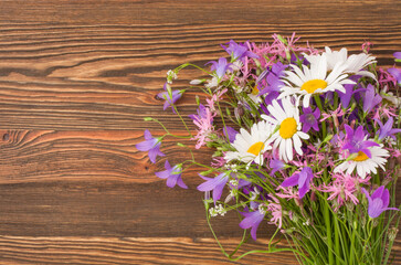 A bouquet of wildflowers lies on an old wooden surface