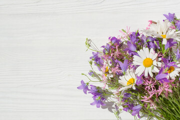 A bouquet of wildflowers lie on a white wooden surface