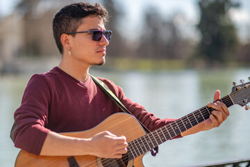 Close-Up of a Passionate Guitarist Engaged in Music by the Lakeside on a Bright Day