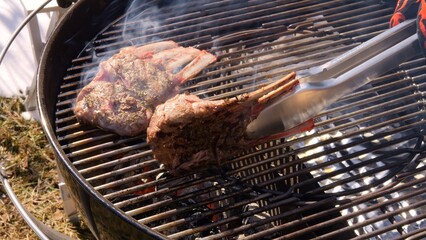 Chef expertly flips meat on grill showcasing precision and skill. Sizzle of grill intensifies as meat cooks to perfection. Witness of grilling as each flip brings out tantalizing aroma of grilled meat