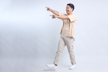 Full Length of Young Man Pointing Index Fingers Sideways to Show Advertisement on Copy Space Isolated on White Background 