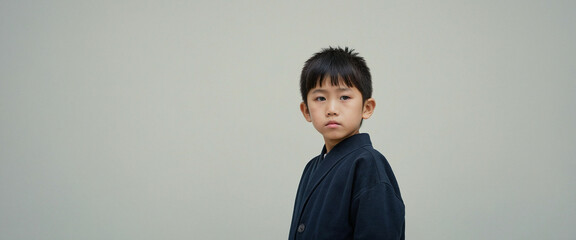 Japanese boy in traditional clothing against a plain background