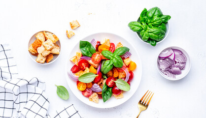 Italian salad with tomatoes, stale bread, red onion, olive oil, salt and green basil, white table...