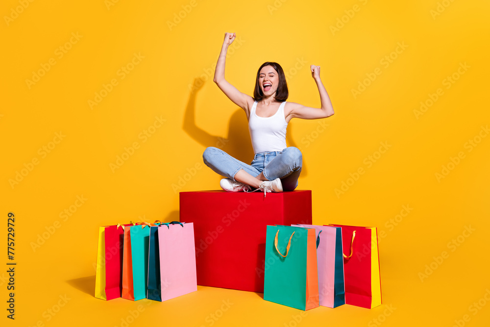 Wall mural Full length photo of lucky impressed woman wear white singlet rising fists enjoying discounts isolated yellow color background