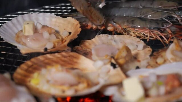 연탄불 위 그릴에서 보글보글 끓으며 익어가는 가리비 치즈구이와 키조개 양념구이 전복구이