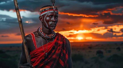 Foto op Aluminium an African warrior with his spear against the backdrop of savanna at sunset. He has a red and white scar on his face, wearing traditional Maasai made from animal skin and beads around his neck © Kien