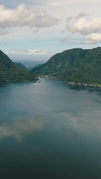 Aerial drone of lake Maninjau in mountains. Tropical landscape with mountains and a lake. Sumatra, Indonesia. Vertical video.