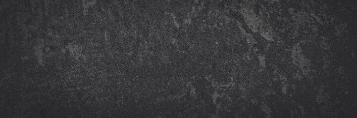 Texture of old concrete wall. Rough faded dark gray concrete surface with spots, cracks, noise and grain. Dark wide panoramic background for grunge style design. Shaded vintage texture with vignette.