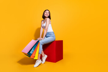 Full length photo of funky dreamy woman wear white singlet holding bargains looking empty space isolated yellow color background