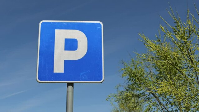 Parking area blue sign with white letter P illuminated by the warm light