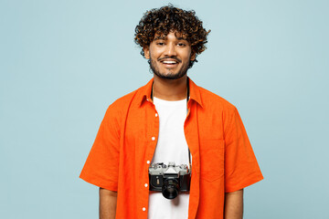Traveler smiling happy Indian man he wears orange casual clothes look camera isolated on plain blue...