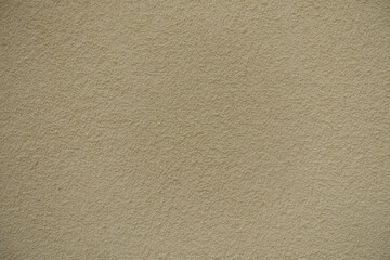 Closeup of wall with coarse light beige roughcast finish