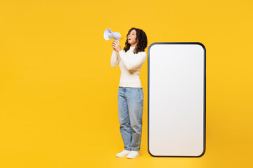 Full body happy little kid teen girl wear white casual clothes big huge blank screen mobile cell phone smartphone with area scream in megaphone isolated on plain yellow background. Lifestyle concept. - 775738538