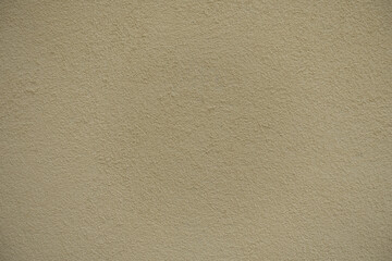 Grainy surface of wall with coarse light beige roughcast finish