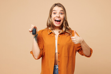 Young surprised woman she wears orange shirt casual clothes hold in hand car keys fob keyless...