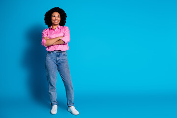 Full length portrait of pretty young woman folded arms look empty space wear pink shirt isolated on blue color background