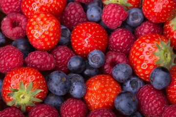 Variety of berries - trawberries, blueberries, raspberries scattered as a full background, top view - 775741904