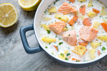 Grey serving pan with lohikeitto or finnish salmon soup, horizontal shot, middle closeup, selective...