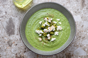 Bowl with broccoli and spinach cream-soup, horizontal shot on a light-brown granite background,...