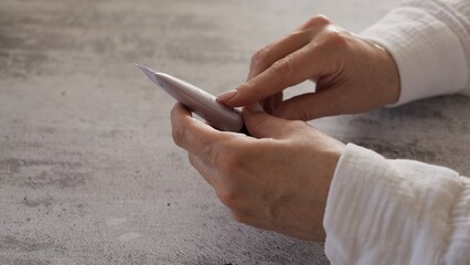 Woman attentively examines cosmetic cream ingredients. With keen eye analyzes cream composition,...