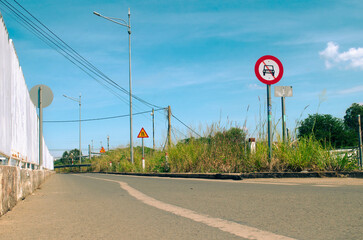 A small rural asphalt road trail in Vietnam, with signboards and powerlines.