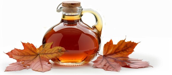A bottle of maple syrup surrounded by leaves