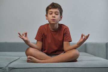 Serene child practices meditation on a couch, symbolizing peace and mindfulness in young minds. A moment of tranquility in a busy world.