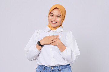 Happy Asian Muslim woman with hands on chest, expresses gratitude with positive mood isolated on white background. Ramadan and Eid Fitr celebration concept