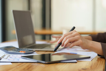 Close-up hand of Asian businesswoman using stylus pen touching on digital tablet screen.
