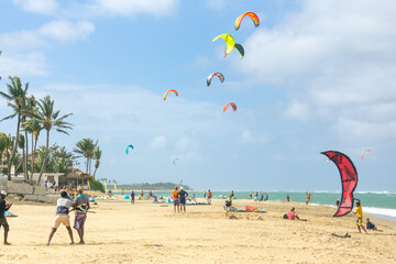 Crowd of active sporty people enjoying kitesurfing holidays and activities on perfect sunny day on Cabarete tropical sandy beach in Dominican Republic