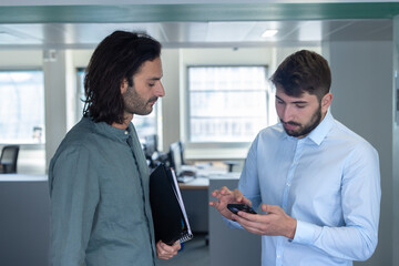 deux collègues, jeunes employés de bureau travaillent en équipe et discutent assis devant un ordinateur portable - 775758913