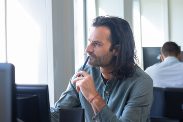 Portrait d'un bel homme de 30 ans qui travaille dans un bureau. il a les cheveux longs et une barbe - 775759305