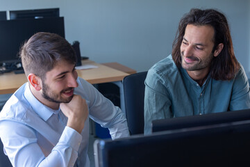 deux jeunes collègues et amis discutent en riant dans leur bureau