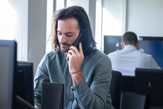 Homme, employ&eacute; de bureau, salari&eacute; d'une entreprise qui travaille devant un ordinateur. Il parle au t&eacute;l&eacute;phone