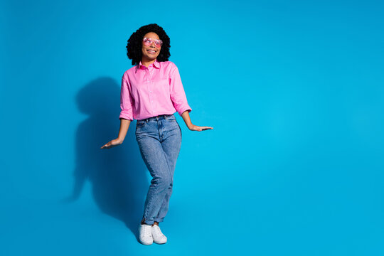 Full size photo of pretty young woman look empty space wear pink shirt isolated on blue color background