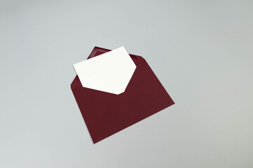 Top view of red envelope, white card on grey background. Post flat lay. Copy space.